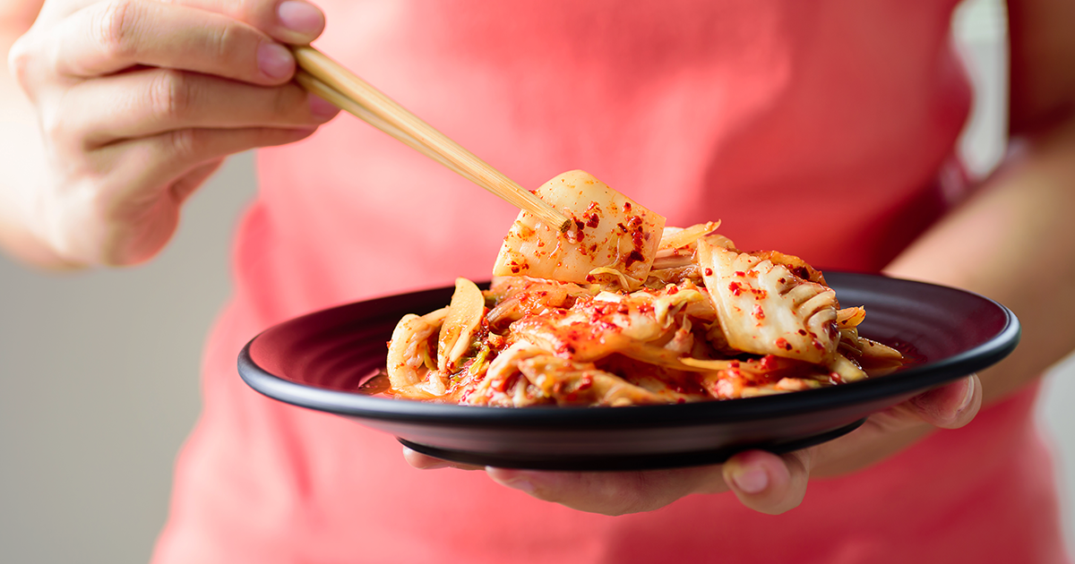 woman holding a plate of kimchi